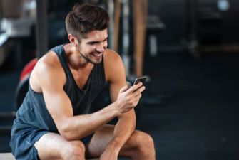 Mand med telefon i fitnesscenter