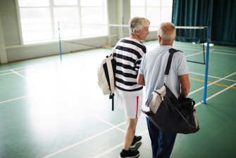 Mænd på badmintonbane med sportstasker
