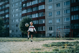 Dreng jonglerer med fodbold foran boligkompleks