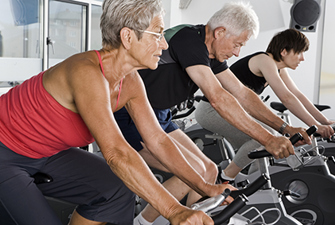 Ældre folk cykler på motionscykler.